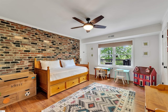 bedroom with light wood-style floors, ornamental molding, brick wall, and ceiling fan