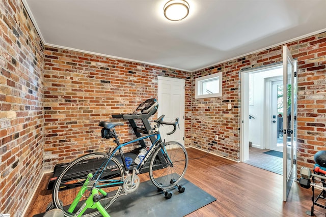 workout room featuring brick wall, wood finished floors, and crown molding