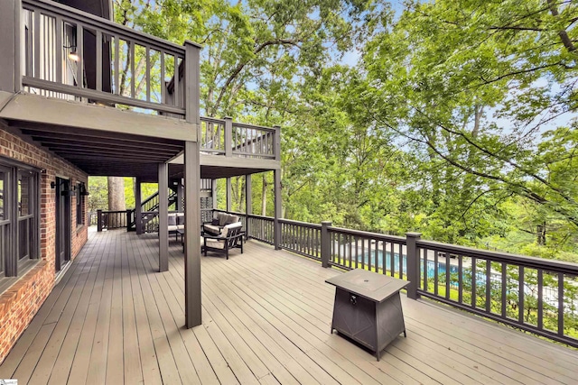 wooden deck featuring outdoor lounge area, stairway, and view of scattered trees