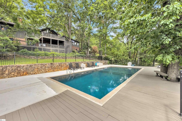view of swimming pool featuring fence, a deck, and a patio area