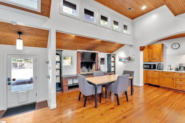dining area featuring wood ceiling, light wood-type flooring, baseboards, arched walkways, and a towering ceiling