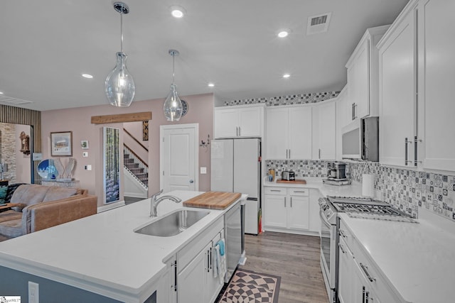 kitchen featuring appliances with stainless steel finishes, a sink, recessed lighting, light countertops, and white cabinetry