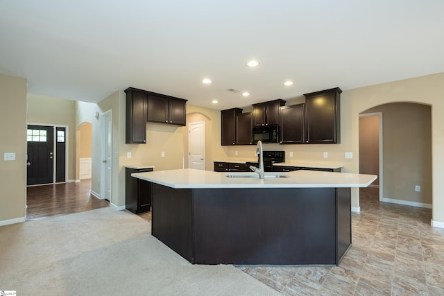 kitchen featuring black microwave, arched walkways, a sink, light countertops, and recessed lighting