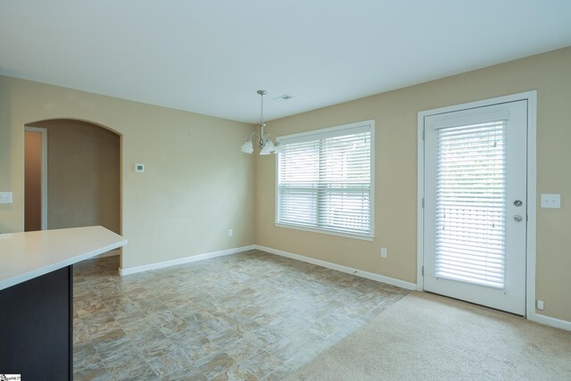 unfurnished dining area featuring a chandelier, baseboards, and arched walkways