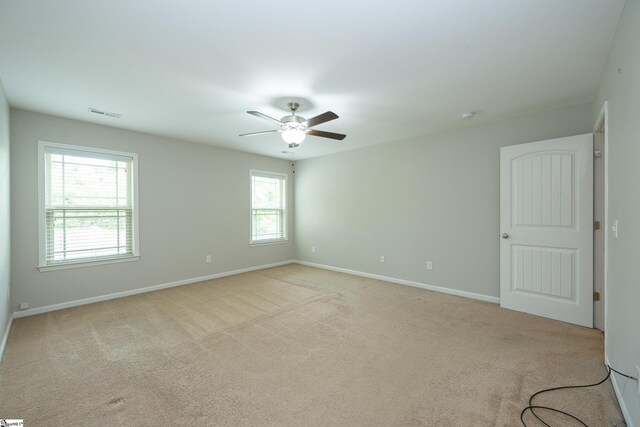 spare room with light carpet, ceiling fan, and baseboards