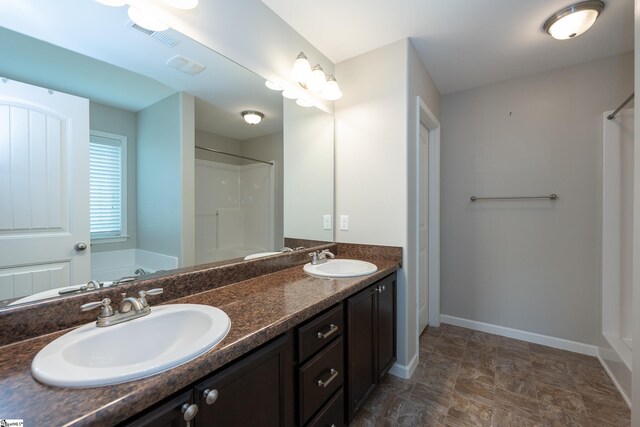 bathroom featuring baseboards, a shower, a bathtub, double vanity, and stone finish flooring