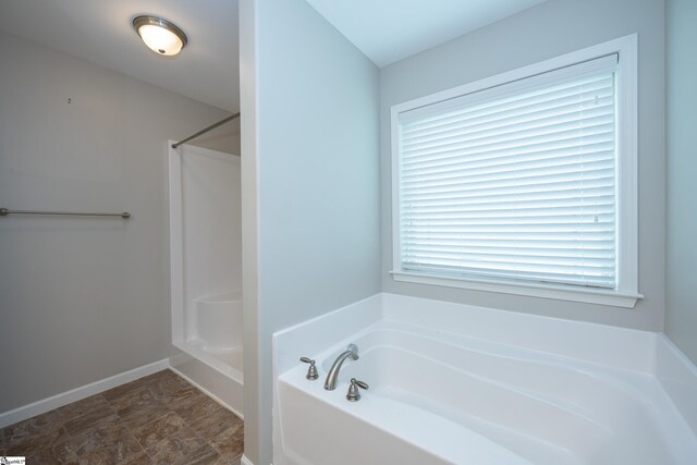 full bath with a bath, a shower, and baseboards