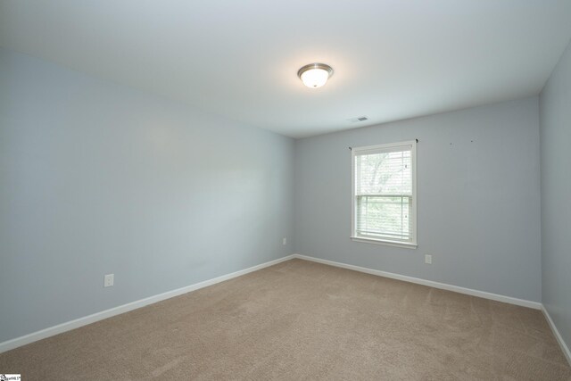empty room featuring light carpet and baseboards