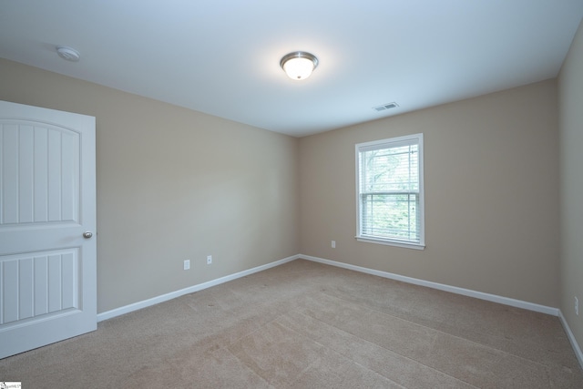 spare room with a smoke detector, light carpet, and baseboards
