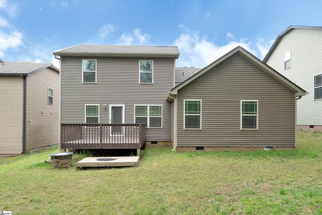 rear view of house with crawl space, a deck, and a lawn