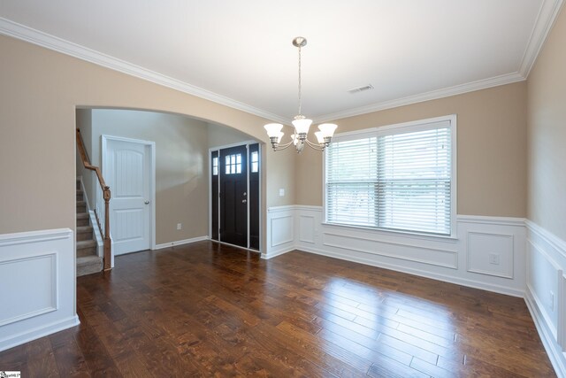 unfurnished dining area featuring a chandelier, arched walkways, wainscoting, ornamental molding, and stairs