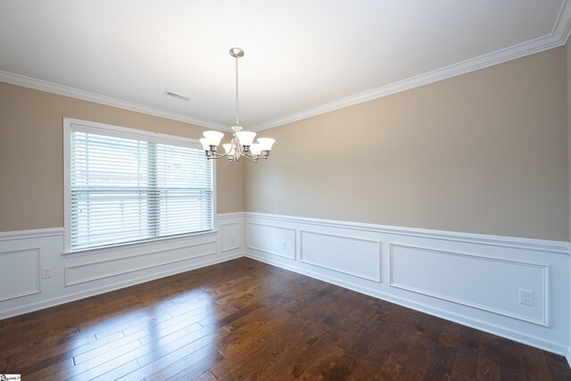 spare room with a chandelier, a wainscoted wall, crown molding, dark wood-type flooring, and a decorative wall