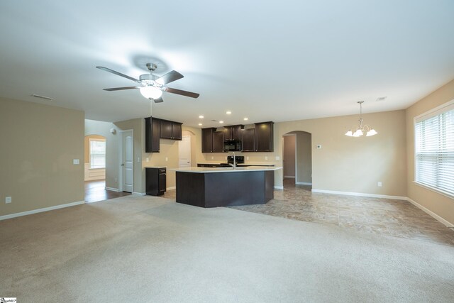 kitchen featuring arched walkways, black microwave, open floor plan, a chandelier, and light colored carpet