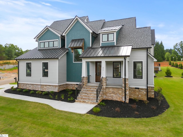 view of front of property featuring a standing seam roof, a front yard, covered porch, metal roof, and a shingled roof