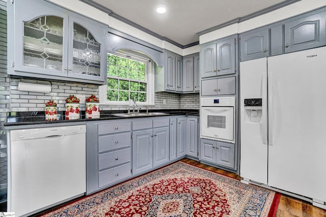 kitchen with white appliances, gray cabinets, dark countertops, a sink, and recessed lighting