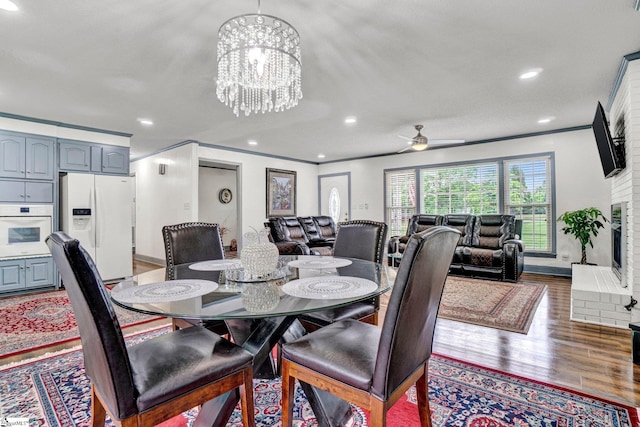 dining space featuring crown molding, wood finished floors, a chandelier, ceiling fan, and recessed lighting