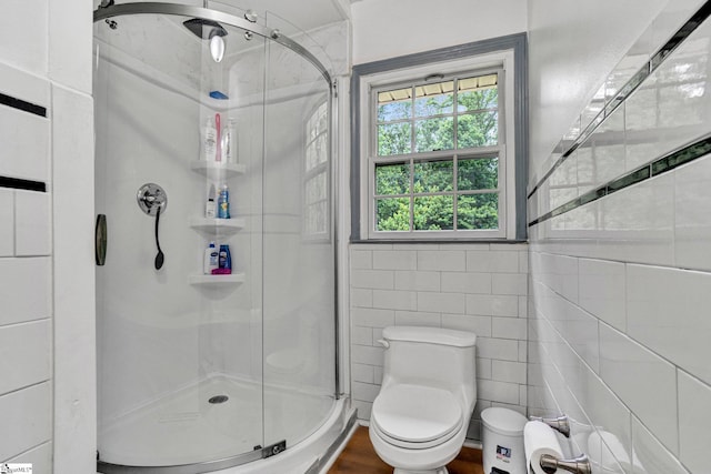 bathroom featuring a shower stall, toilet, and tile walls