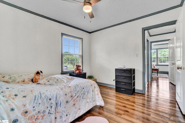 bedroom with ornamental molding, wood finished floors, baseboards, and a ceiling fan