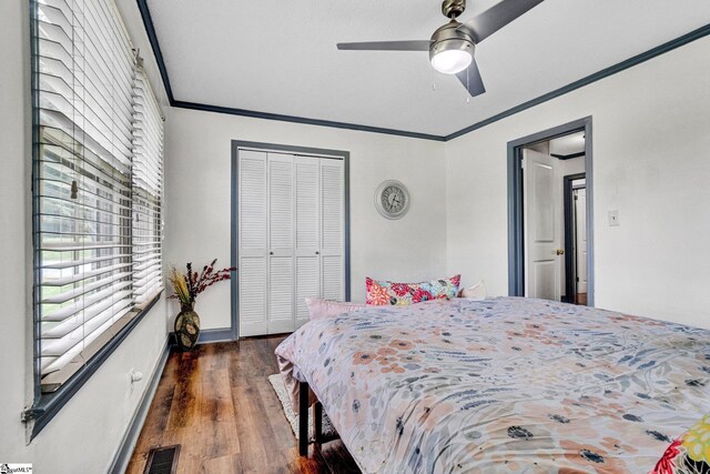 bedroom featuring ornamental molding, dark wood-style flooring, a closet, ceiling fan, and baseboards