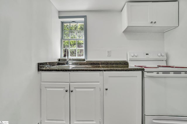 kitchen with electric stove, a sink, white cabinetry, and dark countertops