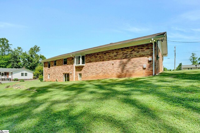 rear view of property featuring a lawn and brick siding