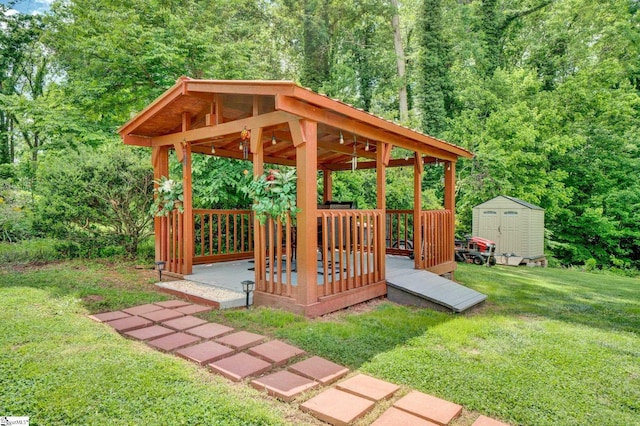 view of property's community featuring a storage unit, a lawn, a gazebo, an outbuilding, and a wooded view