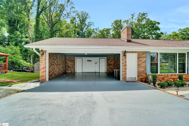 view of front facade with brick siding, driveway, a chimney, and a carport