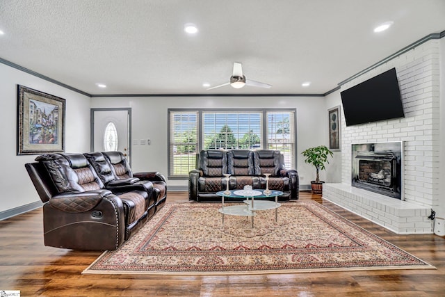 living area with crown molding, a ceiling fan, a fireplace, wood finished floors, and baseboards