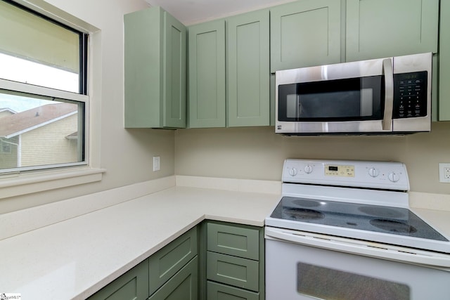 kitchen featuring green cabinets, stainless steel microwave, white electric stove, and light countertops