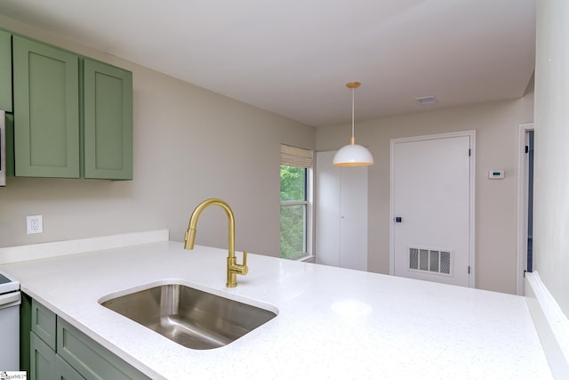 kitchen with a sink, green cabinets, decorative light fixtures, a peninsula, and stainless steel microwave