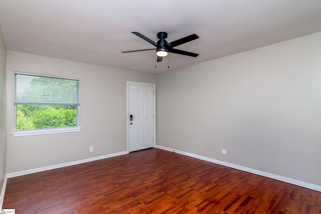 unfurnished room featuring baseboards, a ceiling fan, and dark wood-style flooring