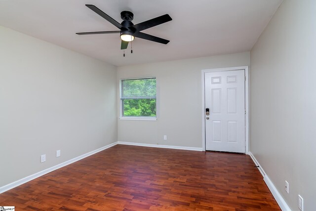 empty room with dark wood-style flooring, ceiling fan, and baseboards