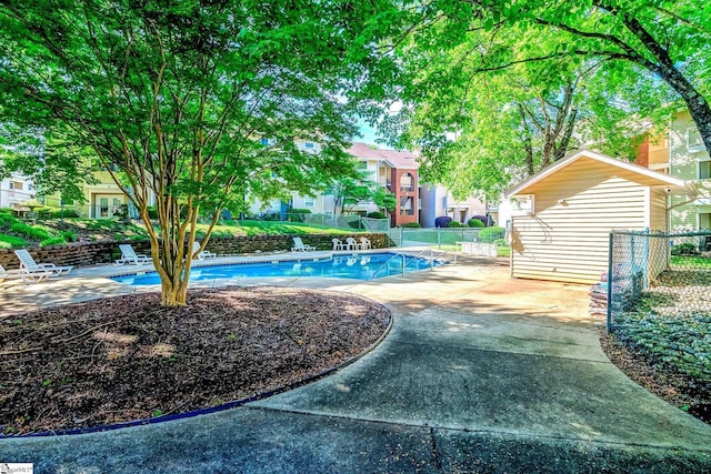 community pool featuring fence, a patio area, and a residential view