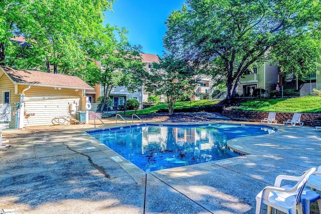 community pool with central air condition unit, fence, and a patio