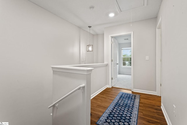 corridor featuring an upstairs landing, attic access, wood finished floors, and baseboards