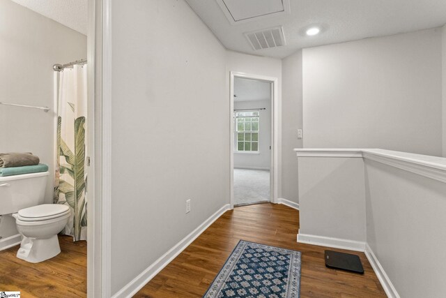 hallway with wood finished floors, baseboards, and attic access