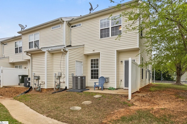 rear view of property featuring central air condition unit and fence