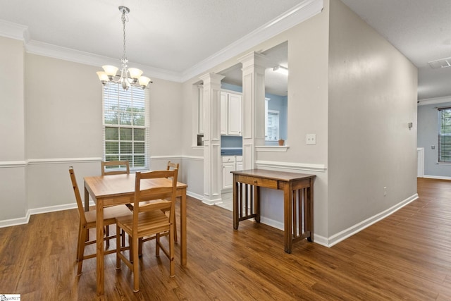 dining room with wood finished floors, ornamental molding, a chandelier, baseboards, and decorative columns