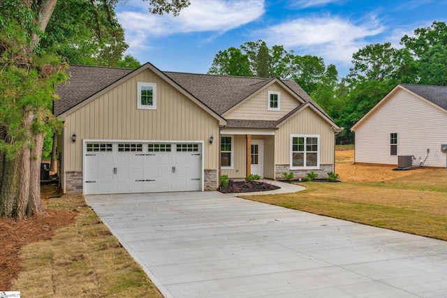 107A W Stewart St, Pelzer, SC 29669 - view of front of home featuring a shingled roof, central AC unit, stone siding, concrete driveway, and a front lawn