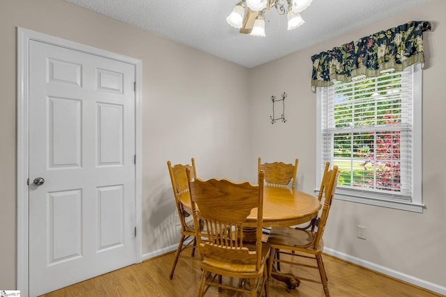 dining area with baseboards, light wood-style flooring, and a textured ceiling