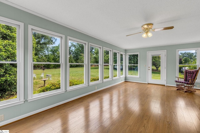 unfurnished sunroom with wood finished floors, baseboards, a textured ceiling, and crown molding