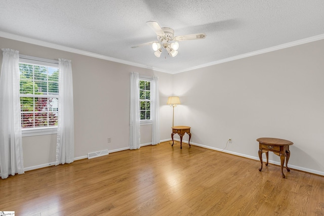unfurnished room featuring a textured ceiling, healthy amount of natural light, light wood-style flooring, a ceiling fan, and ornamental molding