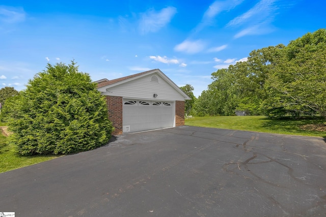 view of side of home featuring brick siding, a lawn, and a garage