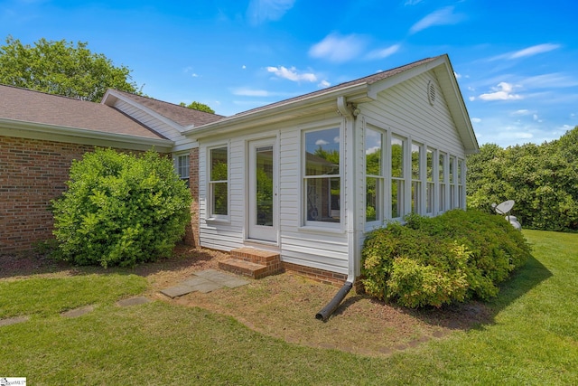 view of side of home featuring a yard, entry steps, and a shingled roof