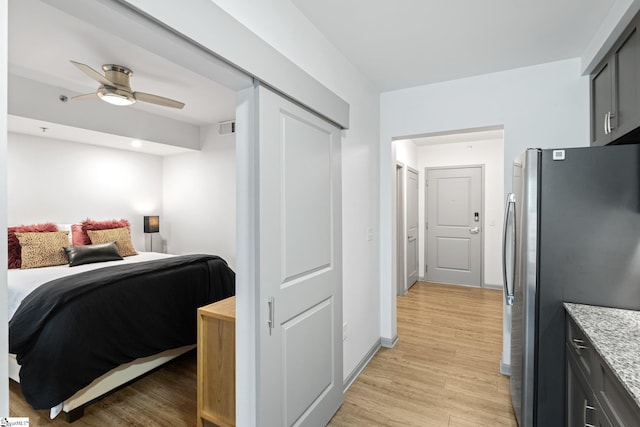 bedroom with freestanding refrigerator and light wood-style floors