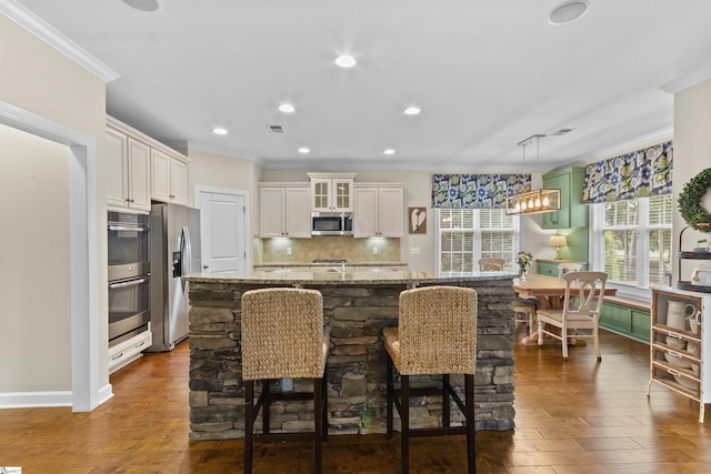 101 Belgian Blue Way, Fountain Inn, SC 29644 - kitchen with appliances with stainless steel finishes, ornamental molding, decorative backsplash, light stone countertops, and a center island with sink