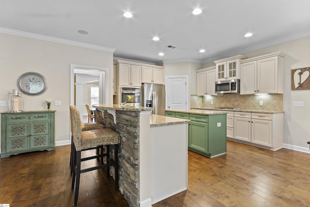 101 Belgian Blue Way, Fountain Inn, SC 29644 - kitchen with appliances with stainless steel finishes, an island with sink, dark wood-style floors, tasteful backsplash, and ornamental molding