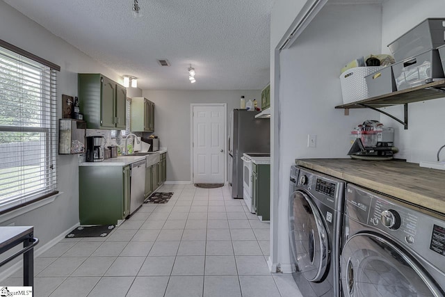 221 Twin Falls Dr, Simpsonville, SC 29680 - clothes washing area featuring washer and clothes dryer, a sink, light tile patterned flooring, baseboards, and a textured ceiling