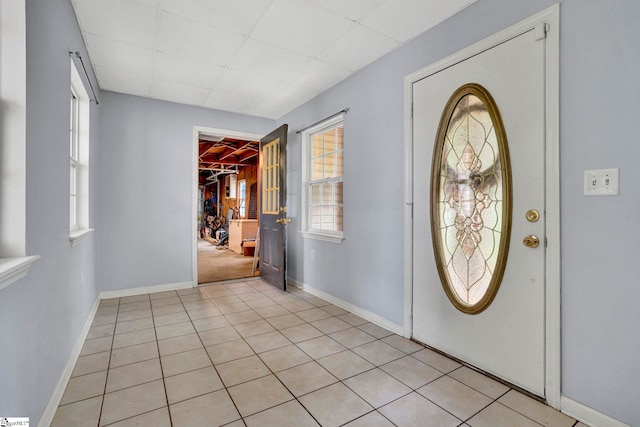 foyer featuring baseboards, light tile patterned floors, and a drop ceiling