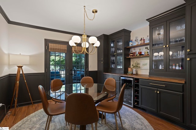dining area with beverage cooler, wainscoting, a dry bar, a chandelier, and dark wood-style floors